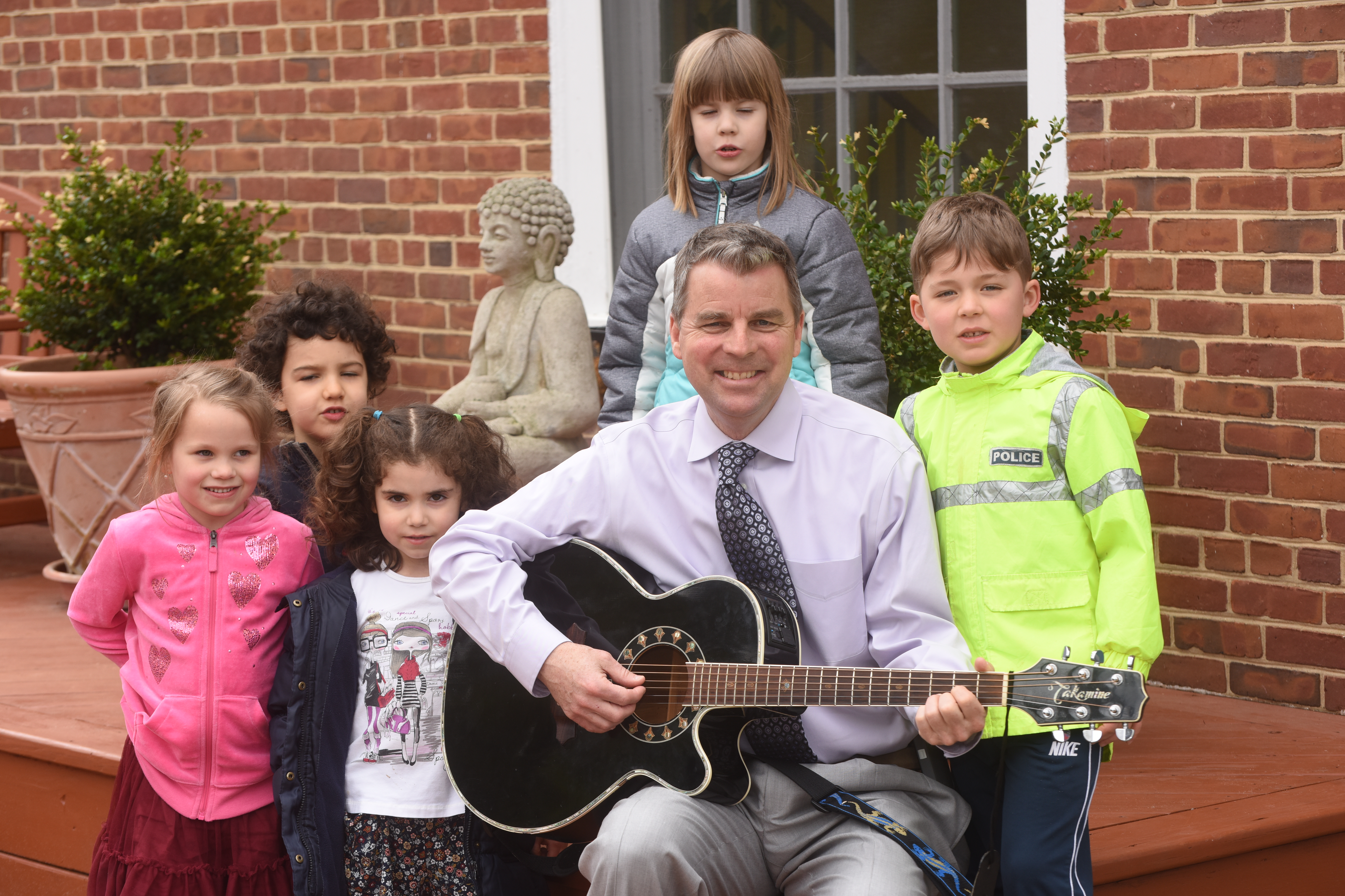 Andrew playing guitar with young Oneness Family School students at school.